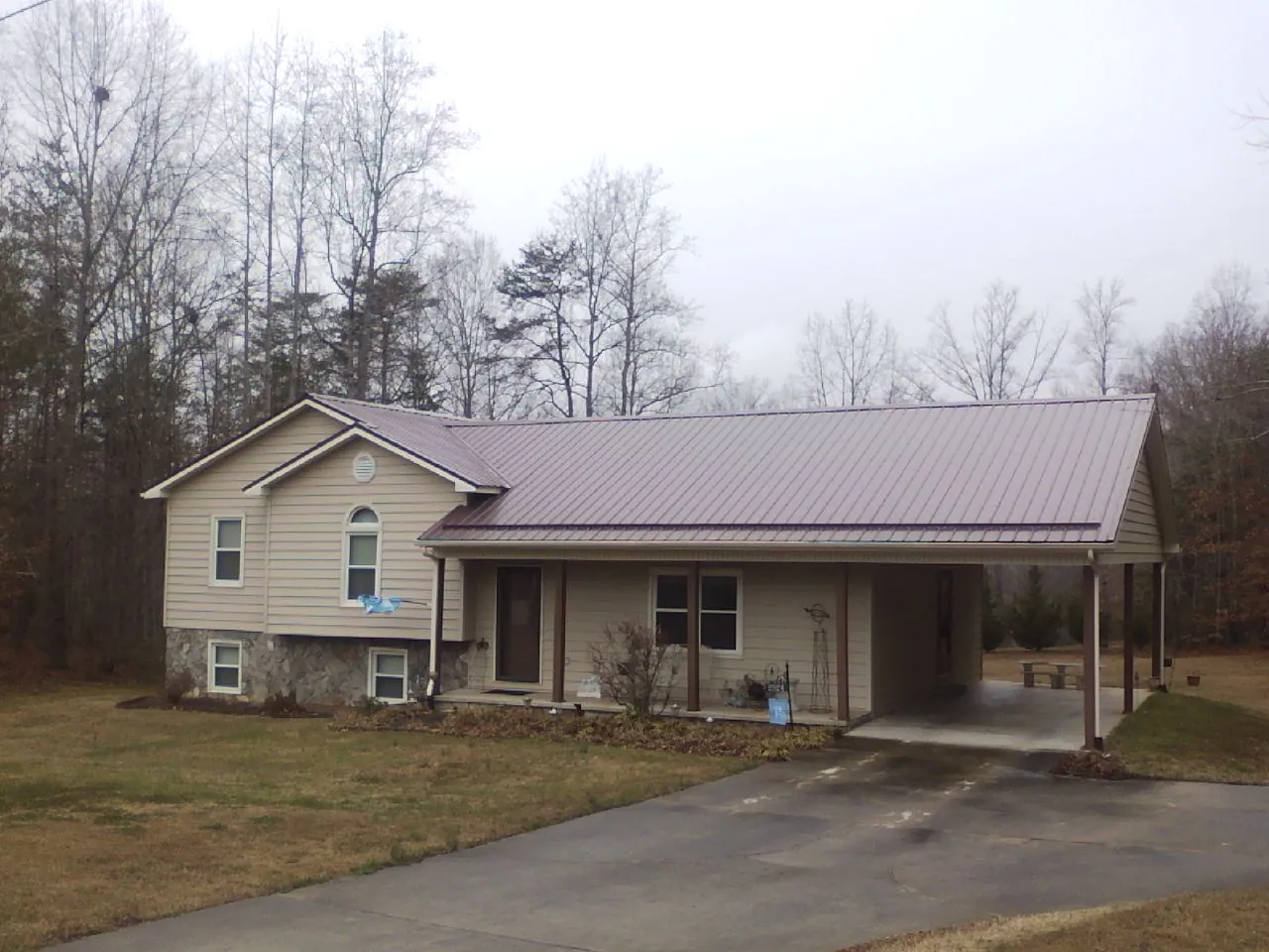 Burgundy metal roof on a tan split level home with an attached carport in Mc Cracken