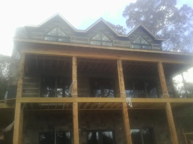 Dormers and porch framing on a large log home under construction — Roof Coating work by our crew in Mc Cracken