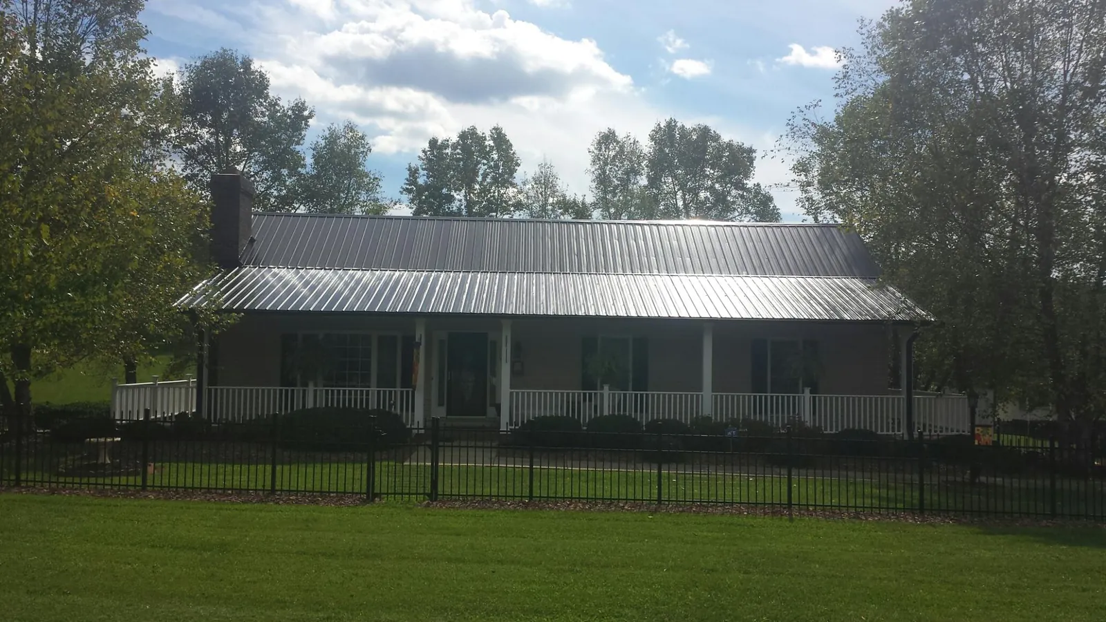 Gray metal roof on a brick ranch with a full width front porch — Gutter Guard Installation work by our crew in Mc Cracken