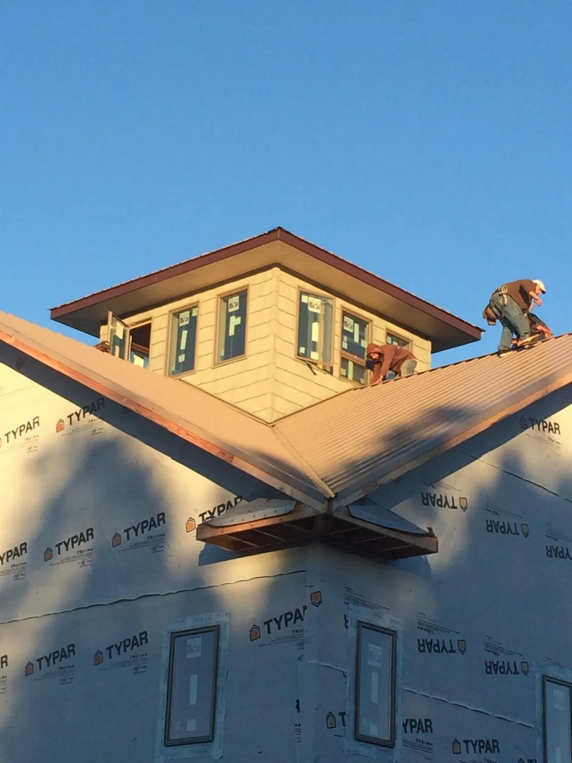Roofers working around a rooftop cupola on a new metal roof at sunset — Roof Waterproofing in Mc Cracken by Roofing Brothers